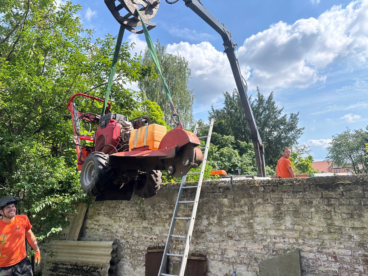 Machine hissée par grue au-dessus d'un mur